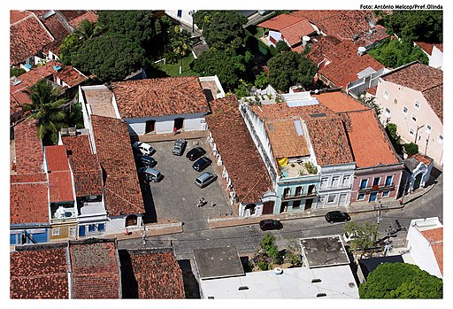 Vista aérea do Mercado da Ribeira em Olinda. A imagem mostra a disposição organizada das construções históricas, rodeadas por ruas de paralelepípedos.